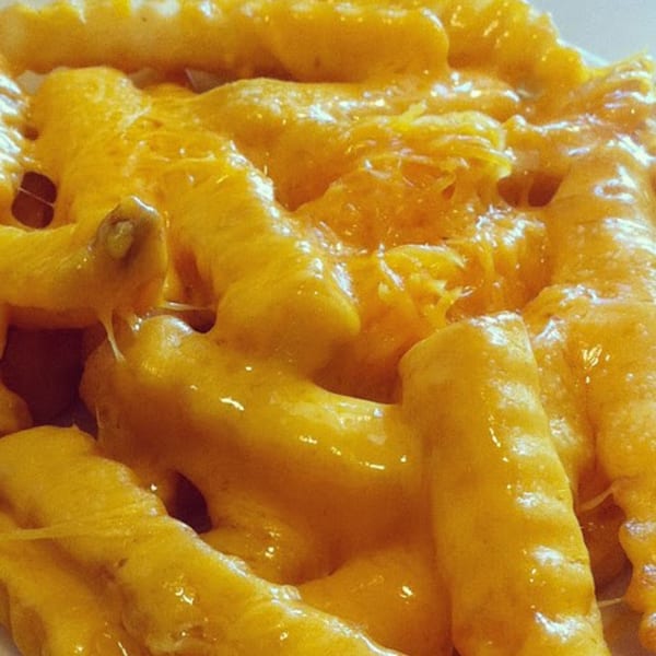 Close-up of golden-yellow macaroni and cheese, with melted cheese strands visible.