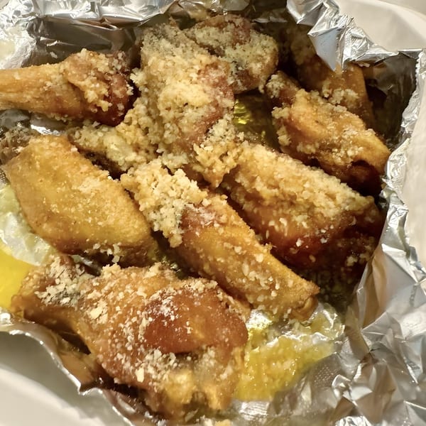 Selfie Subs Food Truck's crispy chicken wings, generously coated in Parmesan cheese, served in foil.